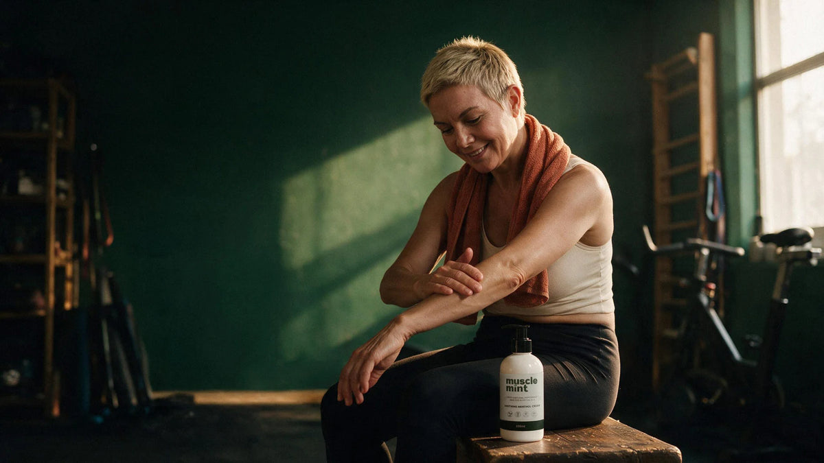Woman applying Muscle Mint soothing menthol cream to her arm after a gym workout, with a 250ml bottle beside her.
