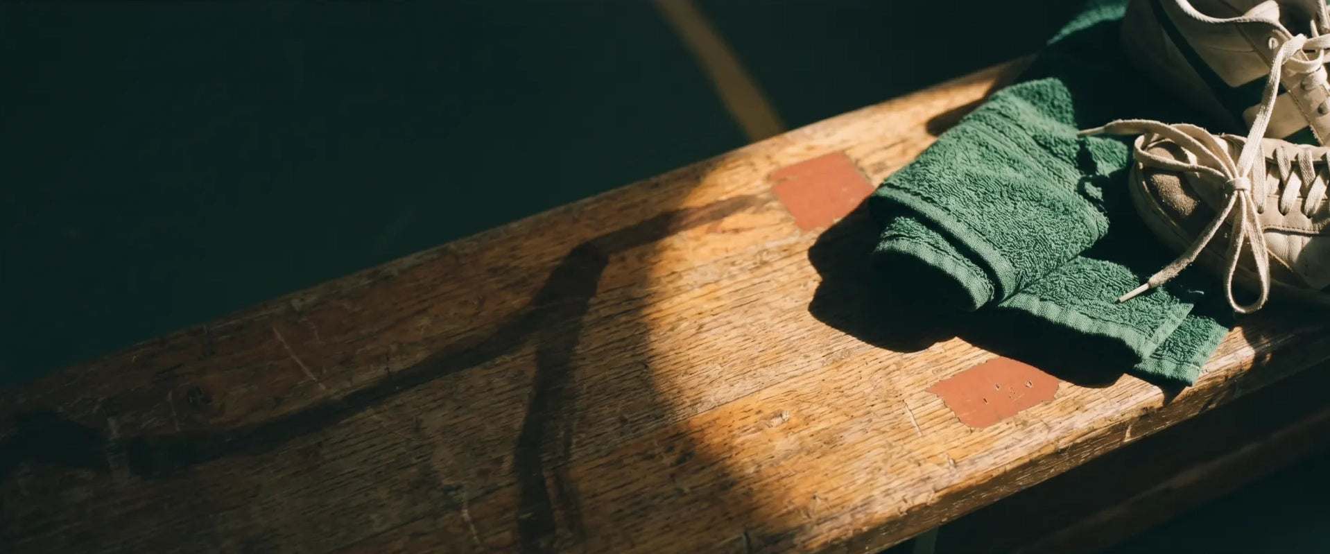 Training shoes and folded towel on a worn wooden bench