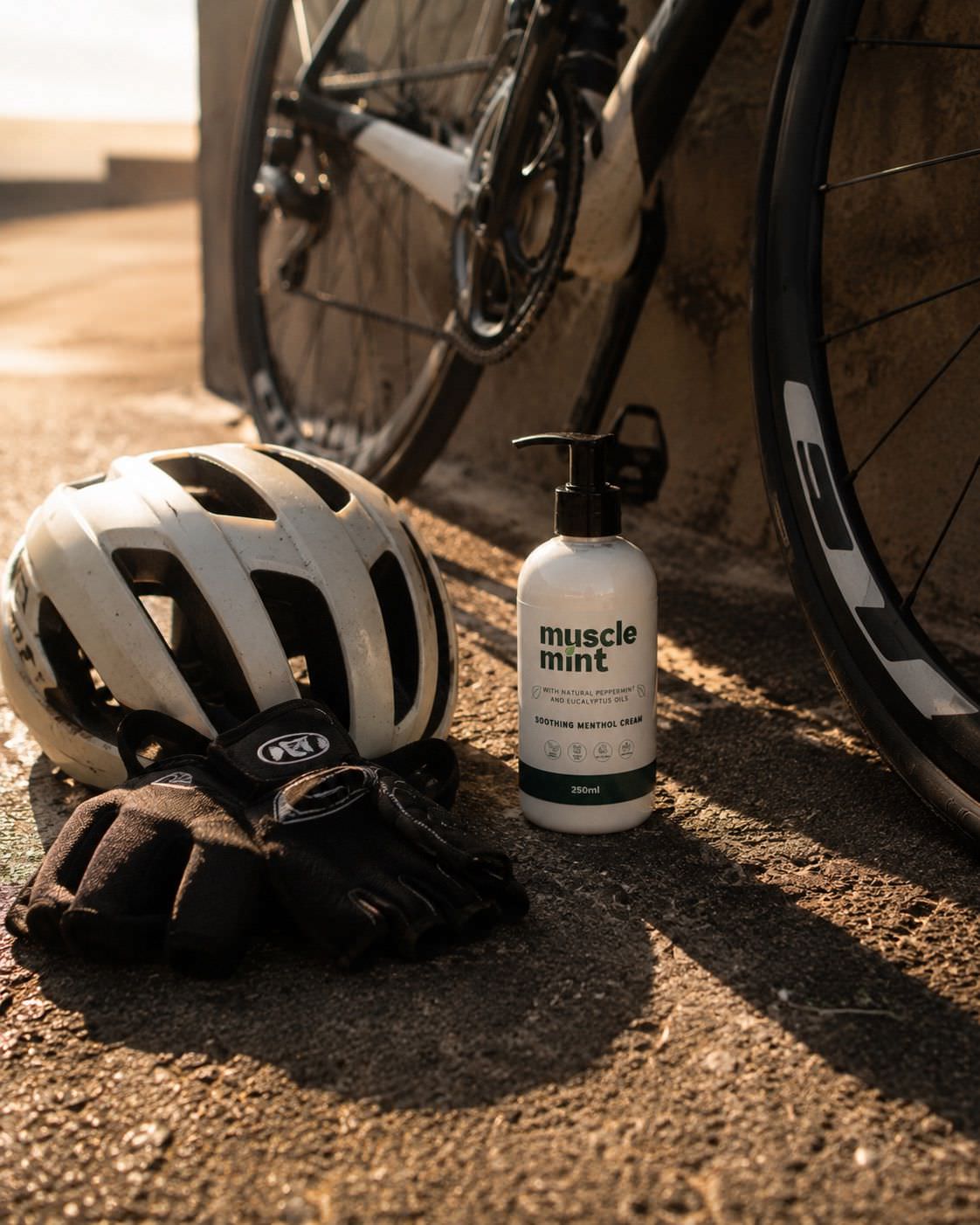 Muscle Mint 250 ml bottle beside a bicycle and cycling kit