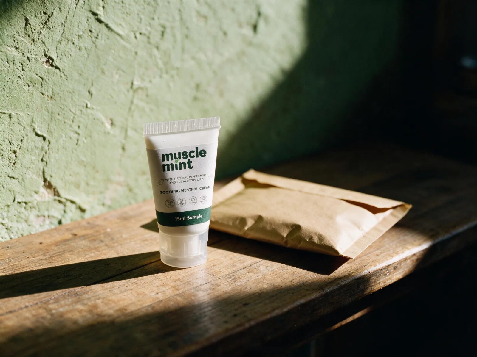 A 15 ml Muscle Mint sample tube on a timber counter beside a kraft postal envelope